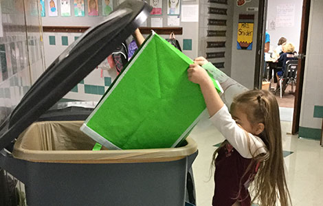 Kindergartner emptying recycle bin